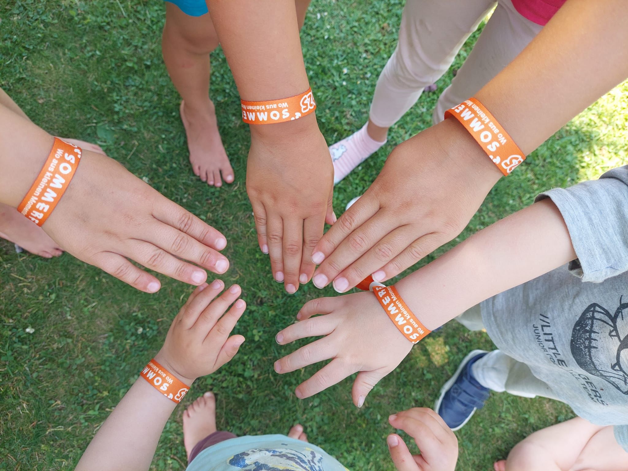 Menschen genießen ein Sommerfest im Freien. Kinder und Eltern lachen und spielen unter Lichterketten.